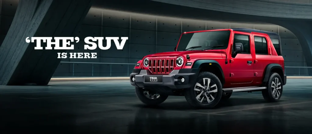 thar roxx price लाल रंगाचे mahindra thar roxx suv गडद पाश्र्वभूमीवर ठळकपणे उभी आहे. तिच्या आधुनिक डिझाइन्स C आकाराचा LED DRLs, 19 inch alloy ल्स आणि मजबूत बांधणी दिसत आहे, जी ऑफ-रोड आणि शहरी वापरासाठी best आहे